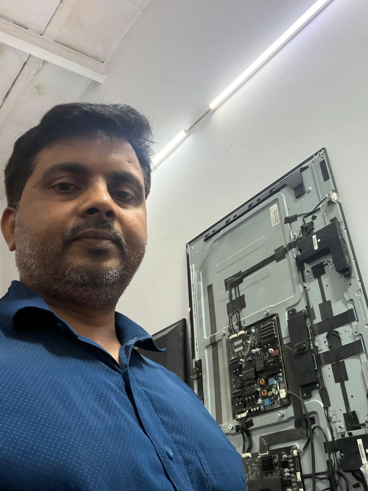 Dharmendra Yadav beside an opened television at the Saraswati Electronics workshop